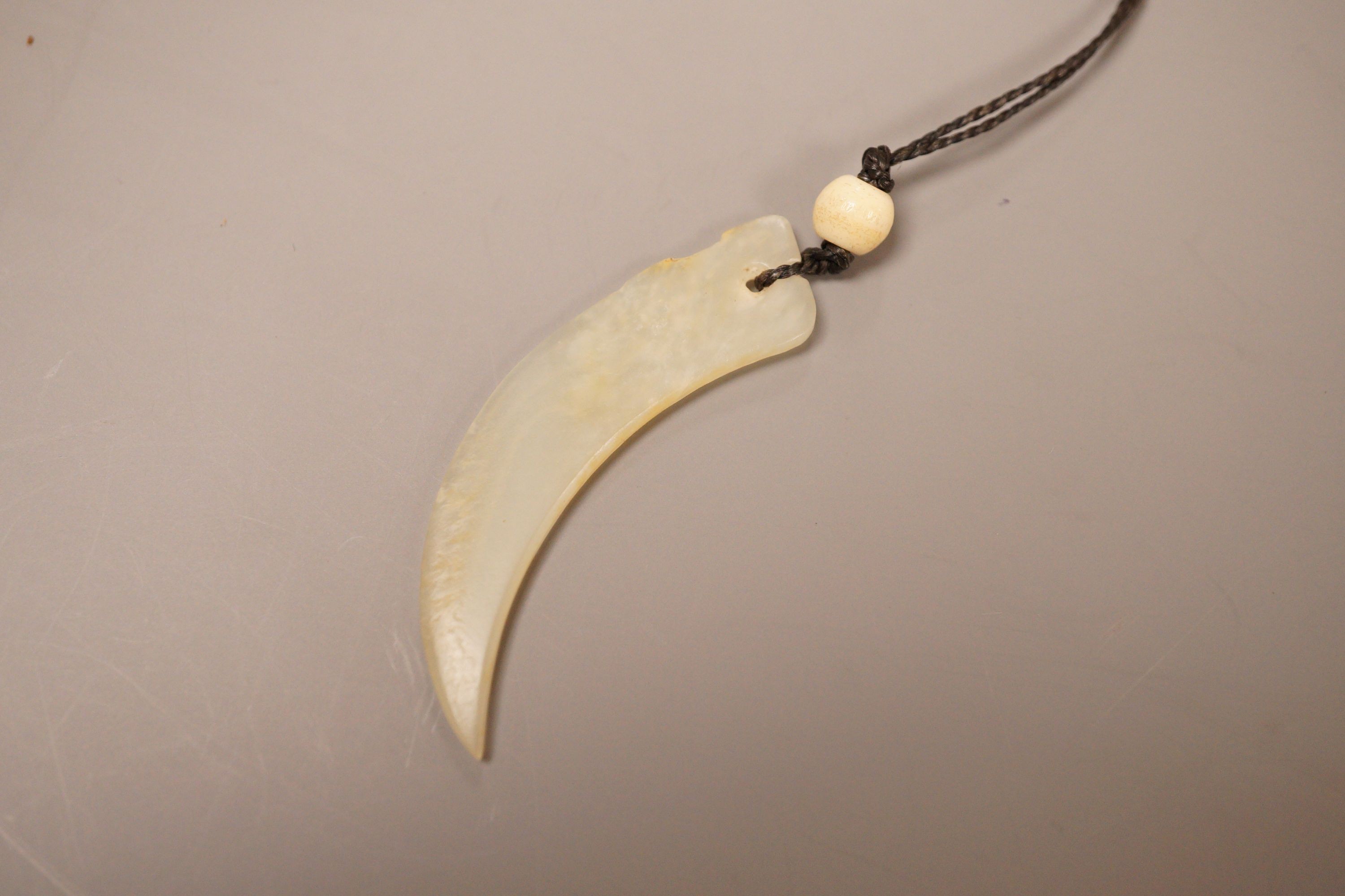 A Chinese jade tooth shaped pendant with bone bead